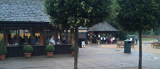 the visitor centre at sandringham house, showing a windowed cafe, smart tidy trees and a shop in the rain